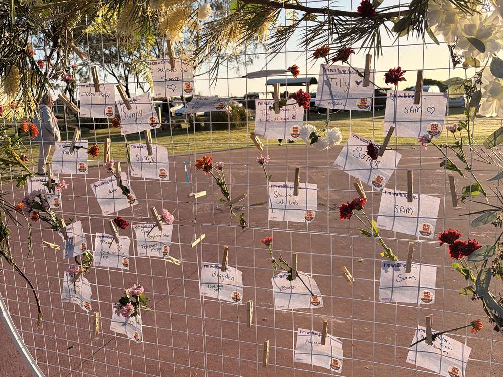 The honouring station: handwritten message cards pegged to a round frame, threaded with flowers